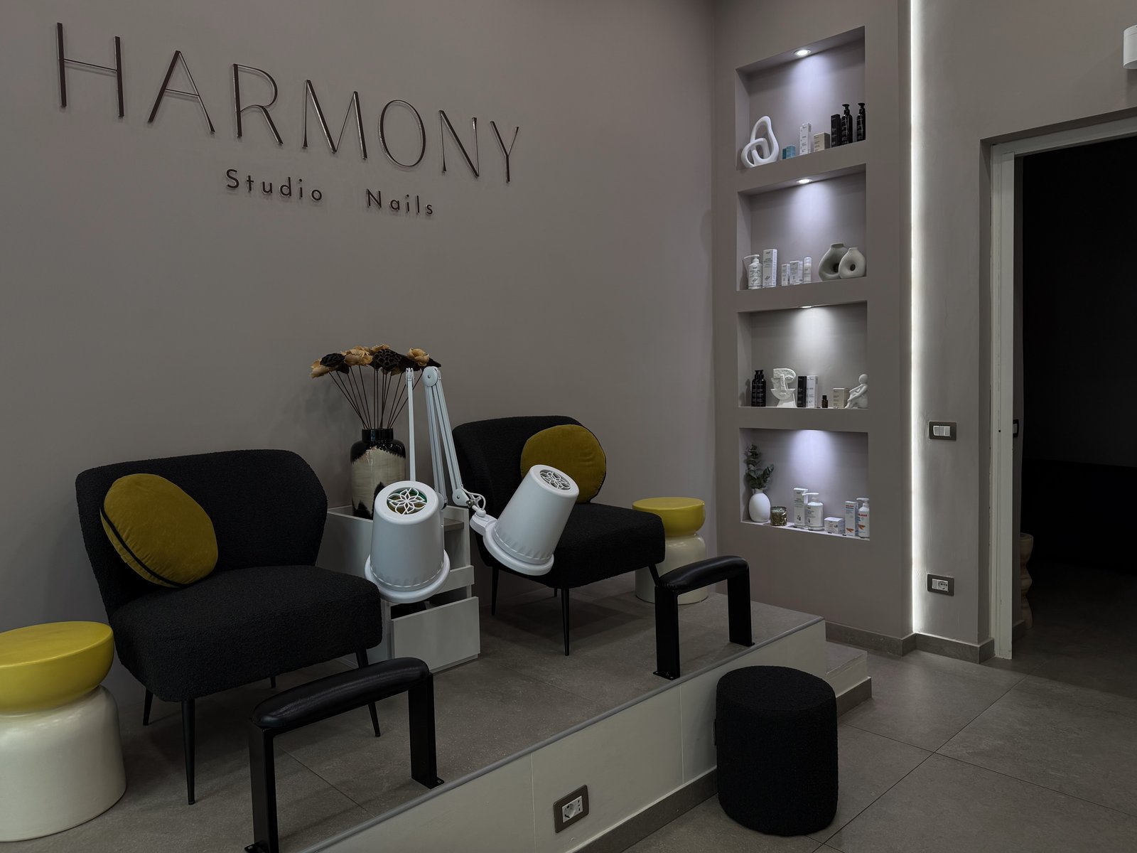 Postazioni manicure con sedie in velluto giallo e illuminazione ad arco